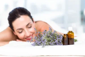 A woman enjoys a spa treatment with lavender and essential oils nearby.