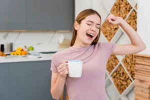 Young woman laughing joyfully, holding a mug in a modern kitchen.