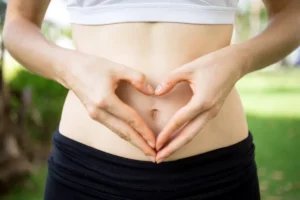 Woman's hands forming a heart shape around her stomach