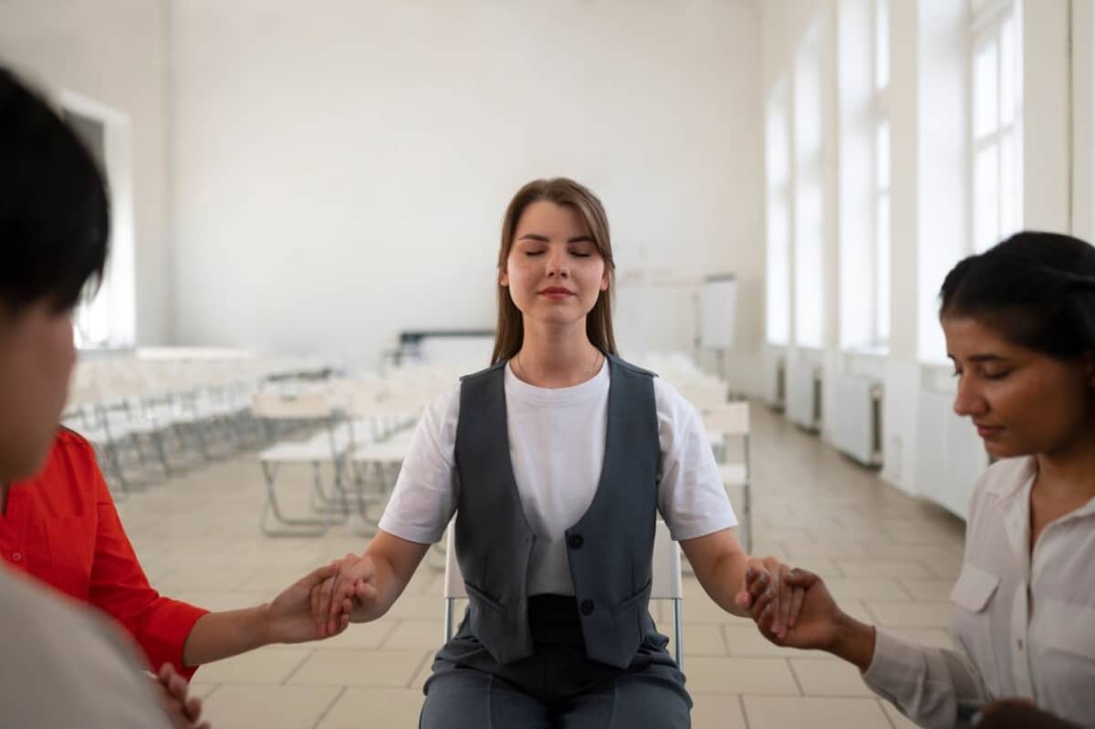 Three women participating in a meditation session in a bright, spacious room.