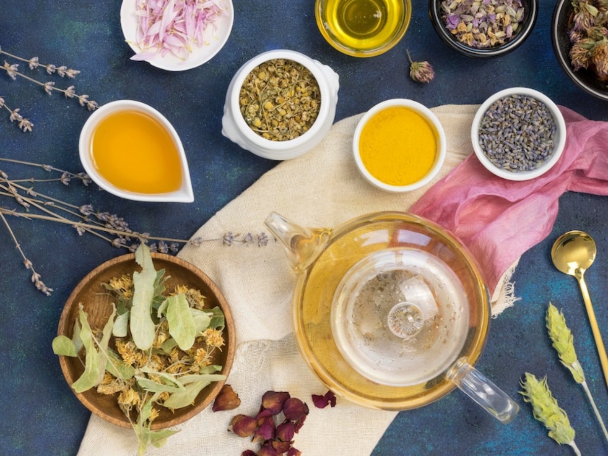 Various herbal teas and ingredients laid out on a blue surface, including lavender, chamomile, and dried herbs.